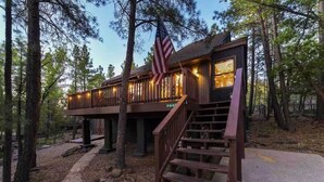 Une cabane en bois avec une terrasse, un escalier et un drapeau américain.