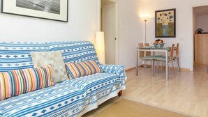 Un salon avec un canapé, une table à manger entourée de chaises, une lampe et un tableau encadré accroché au mur.