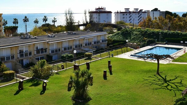 Ett hotell med en pool på taket, utsikt över havet och en välskött gräsmatta.