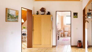 A hallway with a wooden wardrobe, a dining area with a table and chairs, and a bathroom visible through an open door. - (STOE3) Holiday apartment "Waack" - Holiday apartment "Waack" up to 4 persons (Timmendorfer Strand)