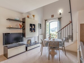 A modern kitchen with a TV, cabinets, and a dining area with a table and chairs.