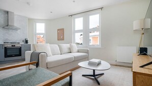 Een moderne woonkamer met een bank, een salontafel en een keuken met een oven.