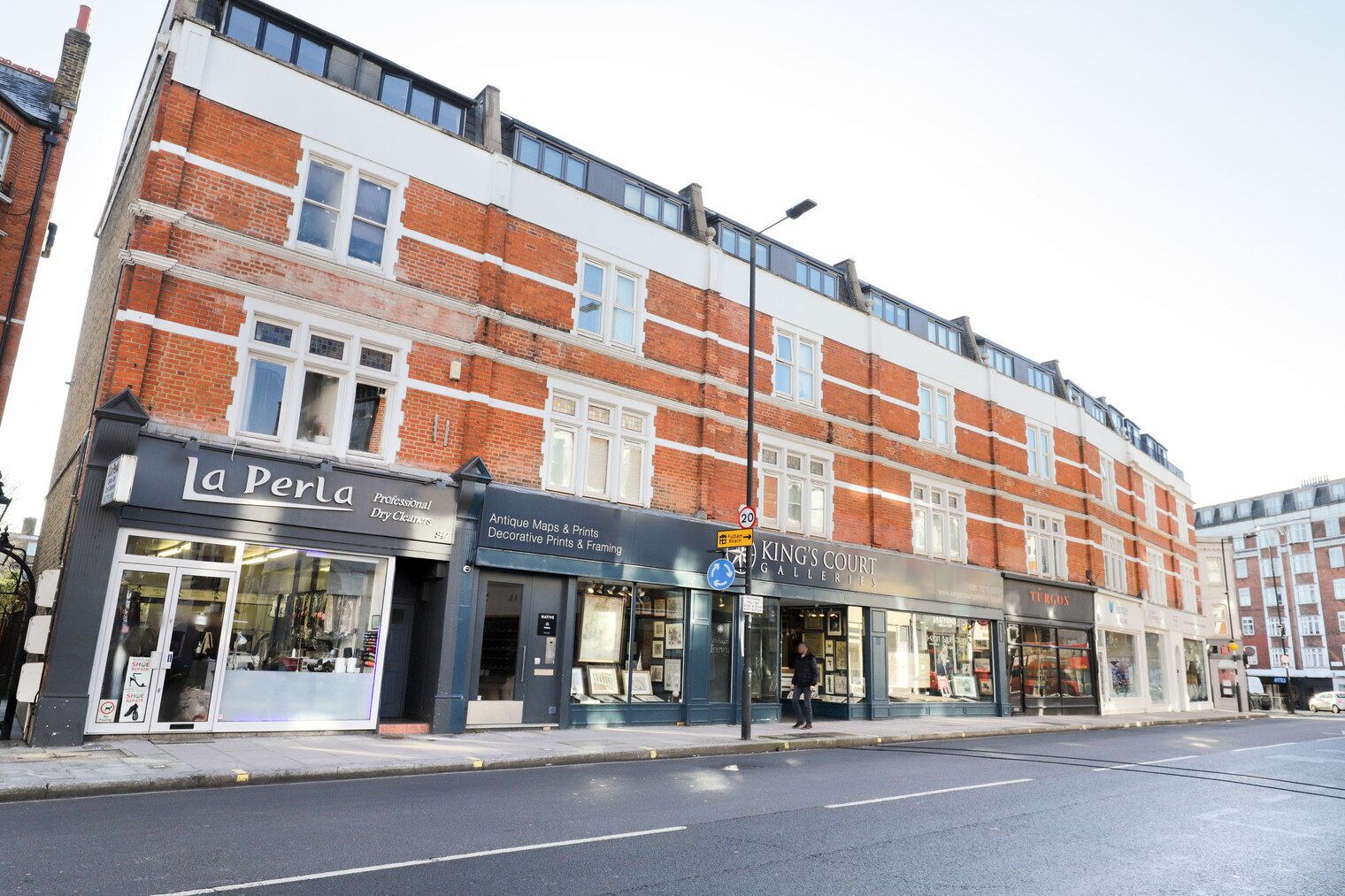 A multi-story building with commercial establishments on the ground floor, including a professional dry cleaning service and a gallery.