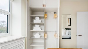 Een slaapkamer met een bed, een inbouwkast met planken en een raam.