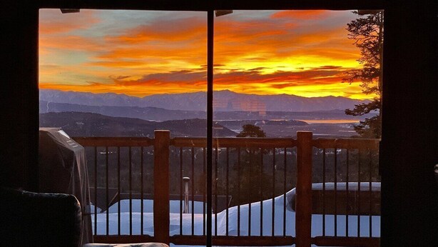 Une chambre avec vue sur un coucher de soleil se reflétant sur les montagnes et donnant sur une piscine.