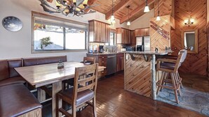 Une cuisine rustique avec des meubles en bois, un grand îlot central doté de tabourets et un lustre.