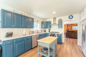 A kitchen with blue cabinets, a wooden island, a stove, and a refrigerator. - Coastwood is a great coastal 4 bedroom house just minutes from the beach! (Fort Bragg)