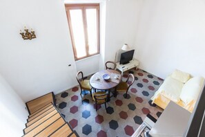 A room with a staircase, a round table with chairs, a television, and a bed.