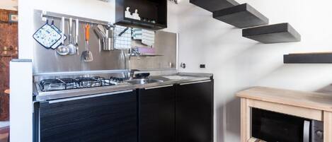 Une cuisine moderne équipée d’une cuisinière à gaz, d’appareils électroménagers en acier inoxydable et d’un four à micro-ondes posé sur un meuble en bois.
