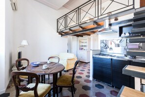 A dining area with a round table, chairs, and a kitchen with a stove and cabinets.