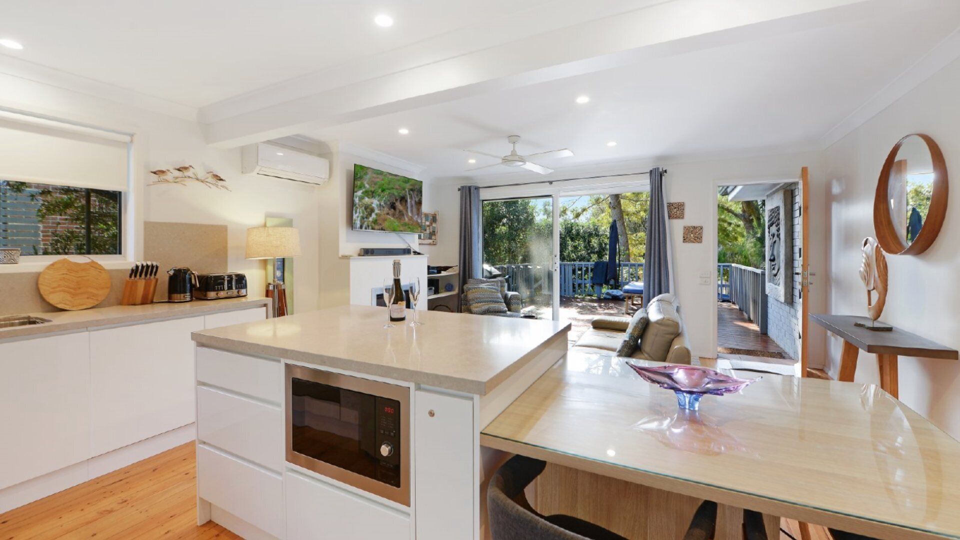 A modern kitchen with a central island, built-in appliances, and a dining area with a glass table.