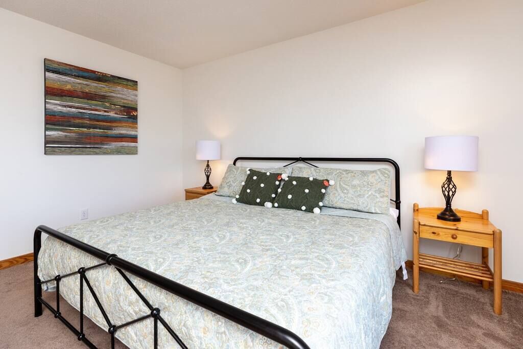 Un dormitorio con una cama, dos mesitas de noche y una lámpara de pared.