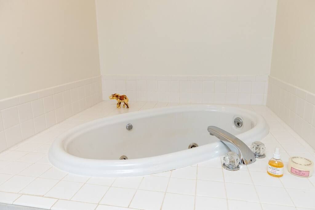 A white bathtub with two faucets, a small decorative item, and two bottles of bath products on the side.