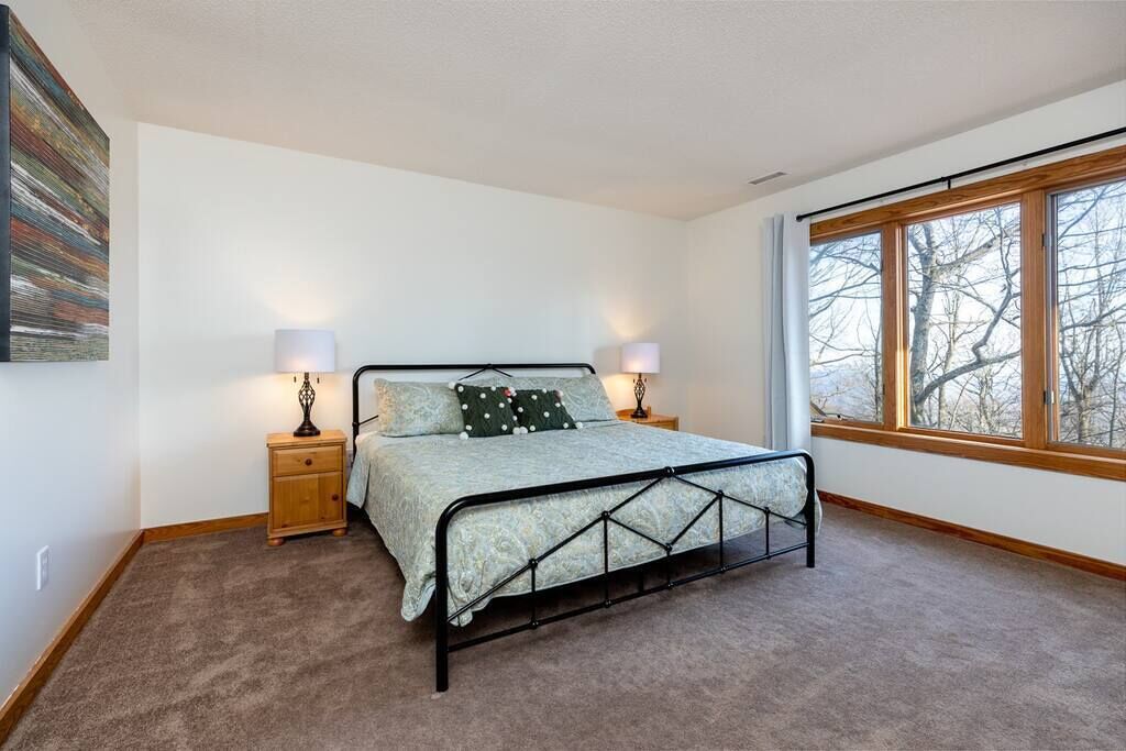 Ein Schlafzimmer mit einem Bett, zwei Nachttischen, einem Fenster und einem Wandbild.
