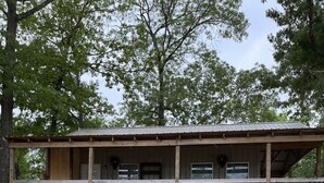 A wooden cabin with a covered porch and multiple windows. - The Texas Rig - Cabin on Caddo Lake (Karnack)