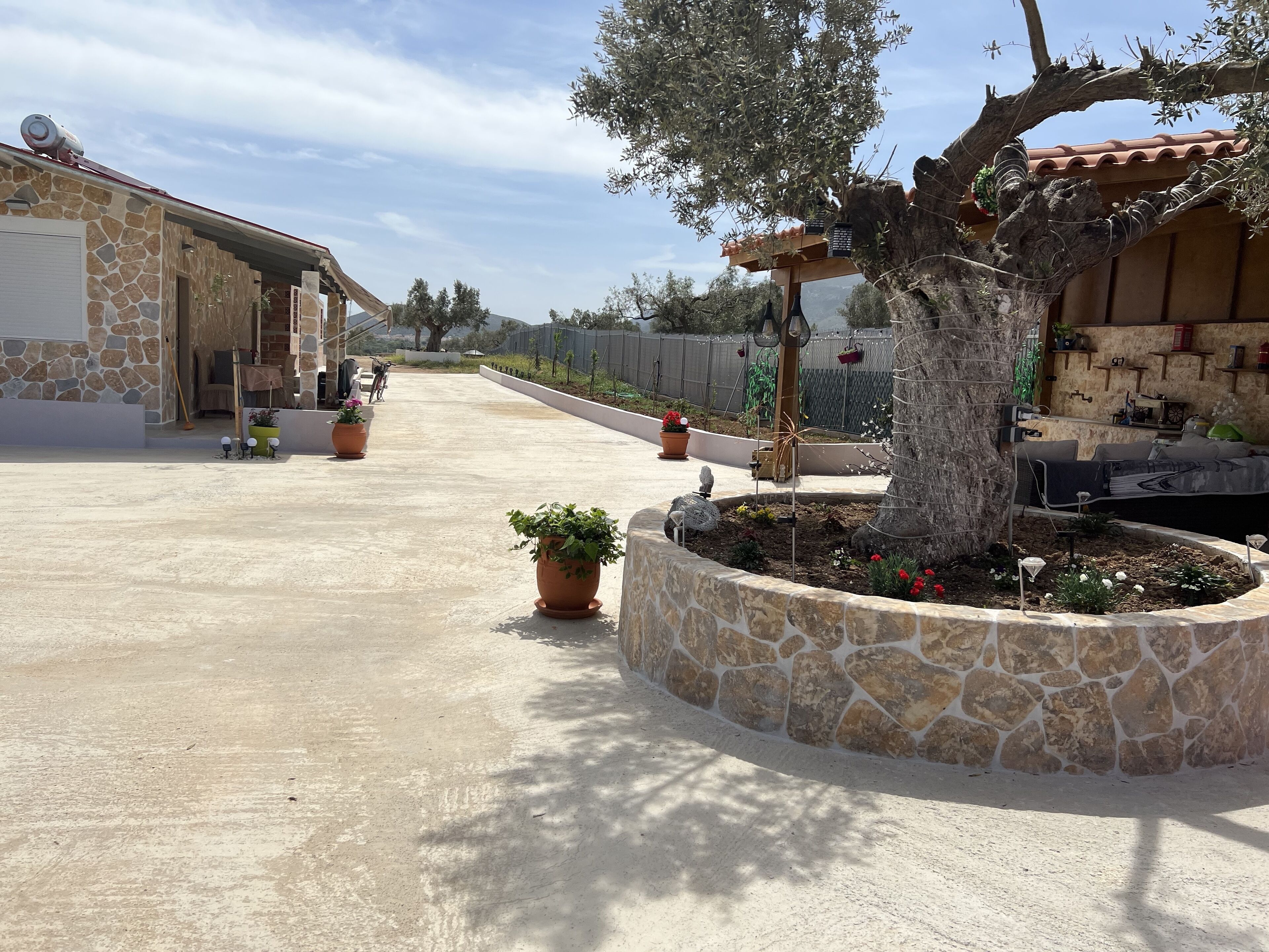 Un vaste espace extérieur agrémenté d’un mur en pierre, de plantes en pot et d’une pergola.