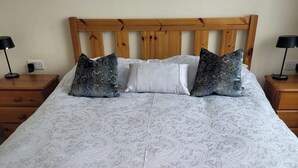 A bed with a patterned bedspread, a wooden headboard, and two bedside tables with lamps. - 1 Bed retreat-Sleeps 2-Secure parking-Garden (Ennis)