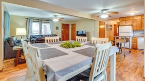 A dining area with a table set for four, a ceiling fan, and a kitchen in the background. - Shell Knob Home w/ Fire Pit, Near Table Rock Lake! (Shell Knob)