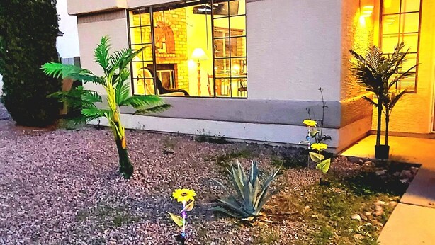 A modern house with a large arched window, a well-maintained garden with gravel and plants, and a stone pathway leading to the entrance. - Cheerful 3 bedroom house with a beautiful backyard (Tucson)