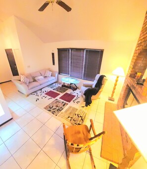 Uma sala de estar com sofá, mesa de centro, tapete estampado e uma cadeira de madeira.