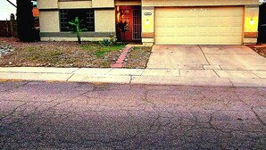A two-story house with a garage, a chimney, and a small front yard with a tree and a pathway. - Cheerful 3 bedroom house with a beautiful backyard (Tucson)