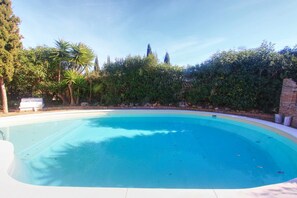 A clear blue swimming pool surrounded by lush greenery and trees. - 2042 Elegant Villa with Garden, heated Pool and Spacious Layout (Marbella)