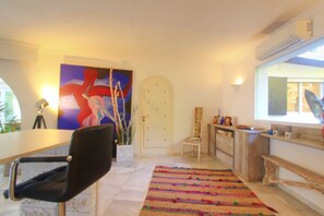 Ein Zimmer mit Esstisch, Stuhl, einem farbenfrohen Teppich, einer weißen Tür und einem Bild an der Wand.