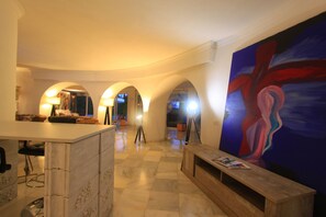 Eine Lobby mit einer Marmor-Rezeption, einem großen abstrakten Gemälde und einem Schachbrettmuster-Boden.