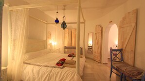 A four-poster bed with a canopy, a wooden chair, and a small table.