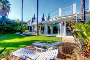Ein modernes Haus mit einer Terrasse, Sitzgelegenheiten im Freien und einem gepflegten Garten.