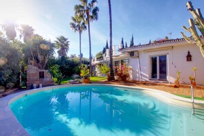 Ein Swimmingpool, umgeben von Palmen und einem Haus mit Balkon.