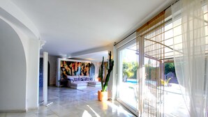 A spacious living area with a large window, a sofa set, and a potted plant.