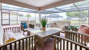 A covered patio area with a wooden table, two sofas, and a ceiling fan.
