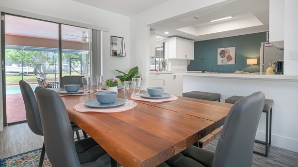 A modern dining area with a wooden table, grey chairs, and a view of the outdoors.