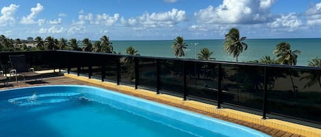 Zwembad met uitzicht op de oceaan en palmbomen.