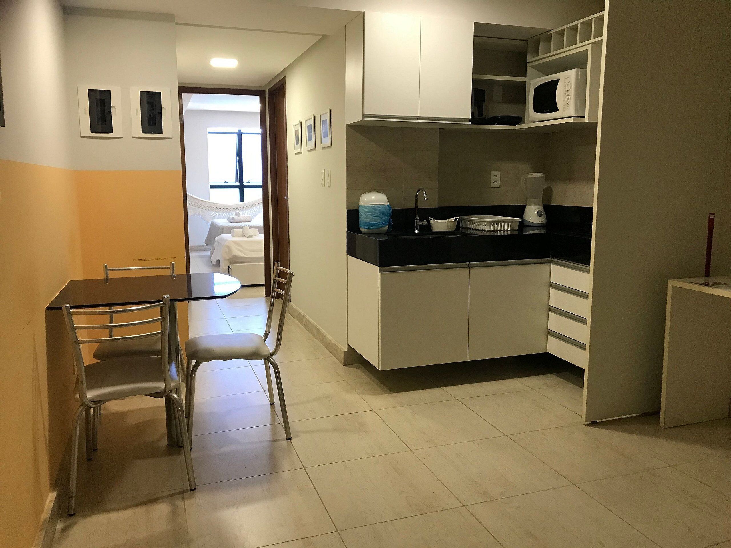 Cocina compacta con comedor, que incluye una mesa y sillas, y vista a un dormitorio.