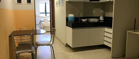 Cocina compacta con comedor, que incluye una mesa y sillas, y vista a un dormitorio.