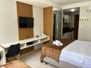 Ett hotellrum med en säng, ett skrivbord med en tv, en stol och en spegel.