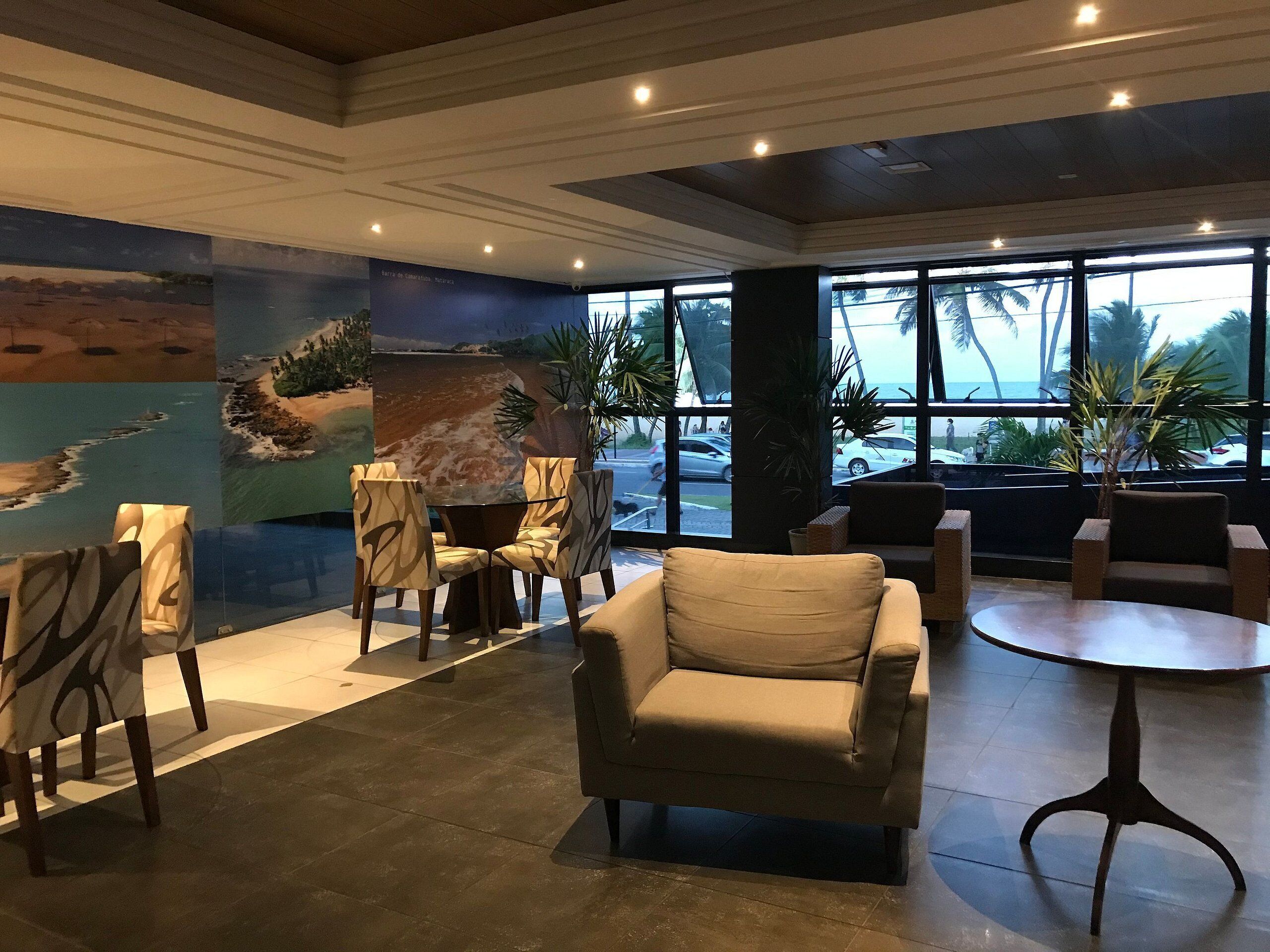 Un vestíbulo con un mural grande, disposición de asientos y ventanas amplias.