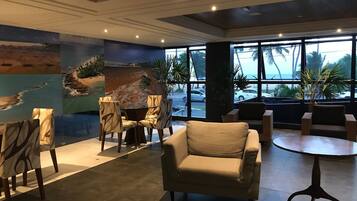 Un vestíbulo con un mural grande, disposición de asientos y ventanas amplias.