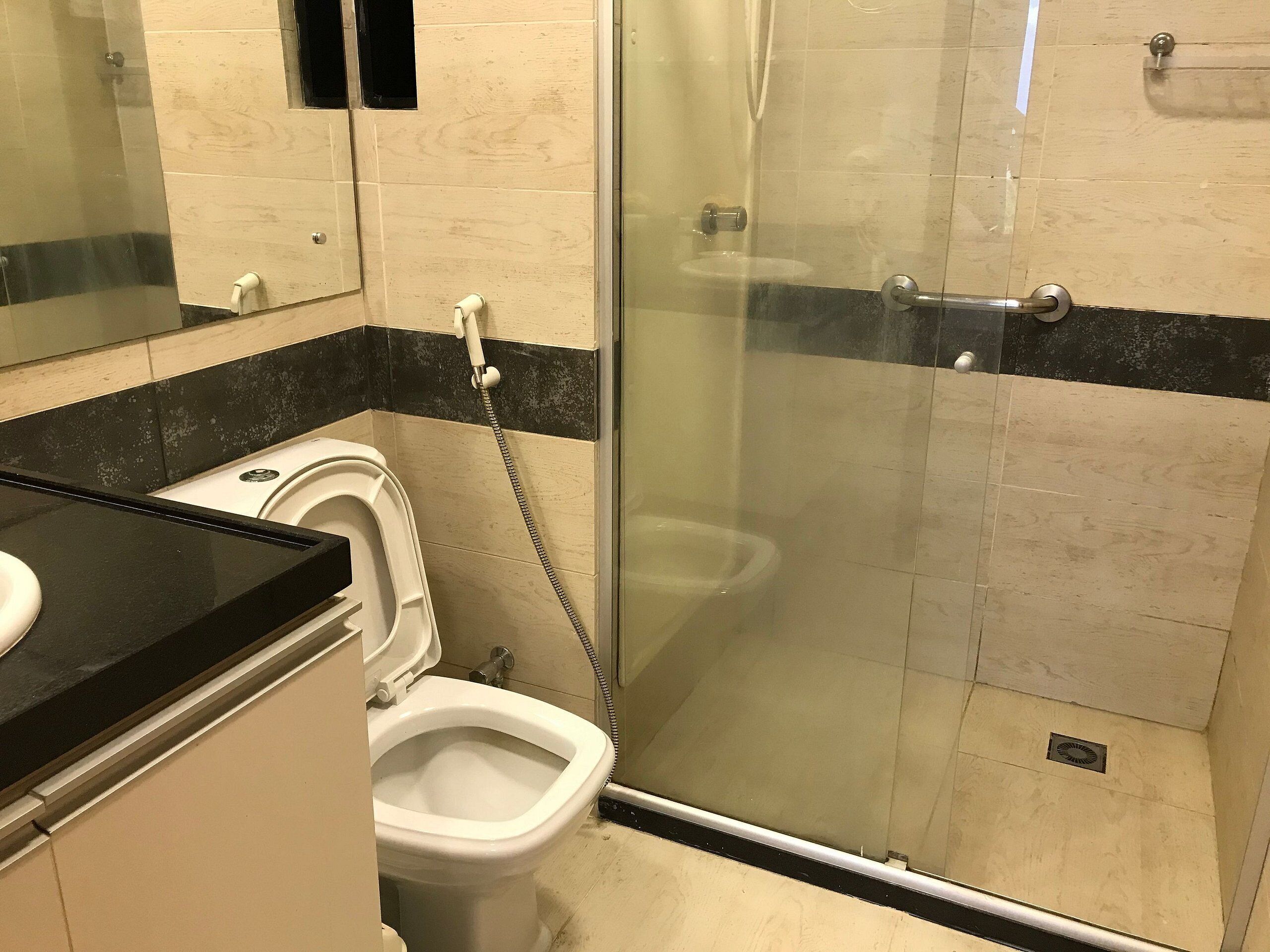A bathroom with a toilet, a shower enclosure, and a sink.