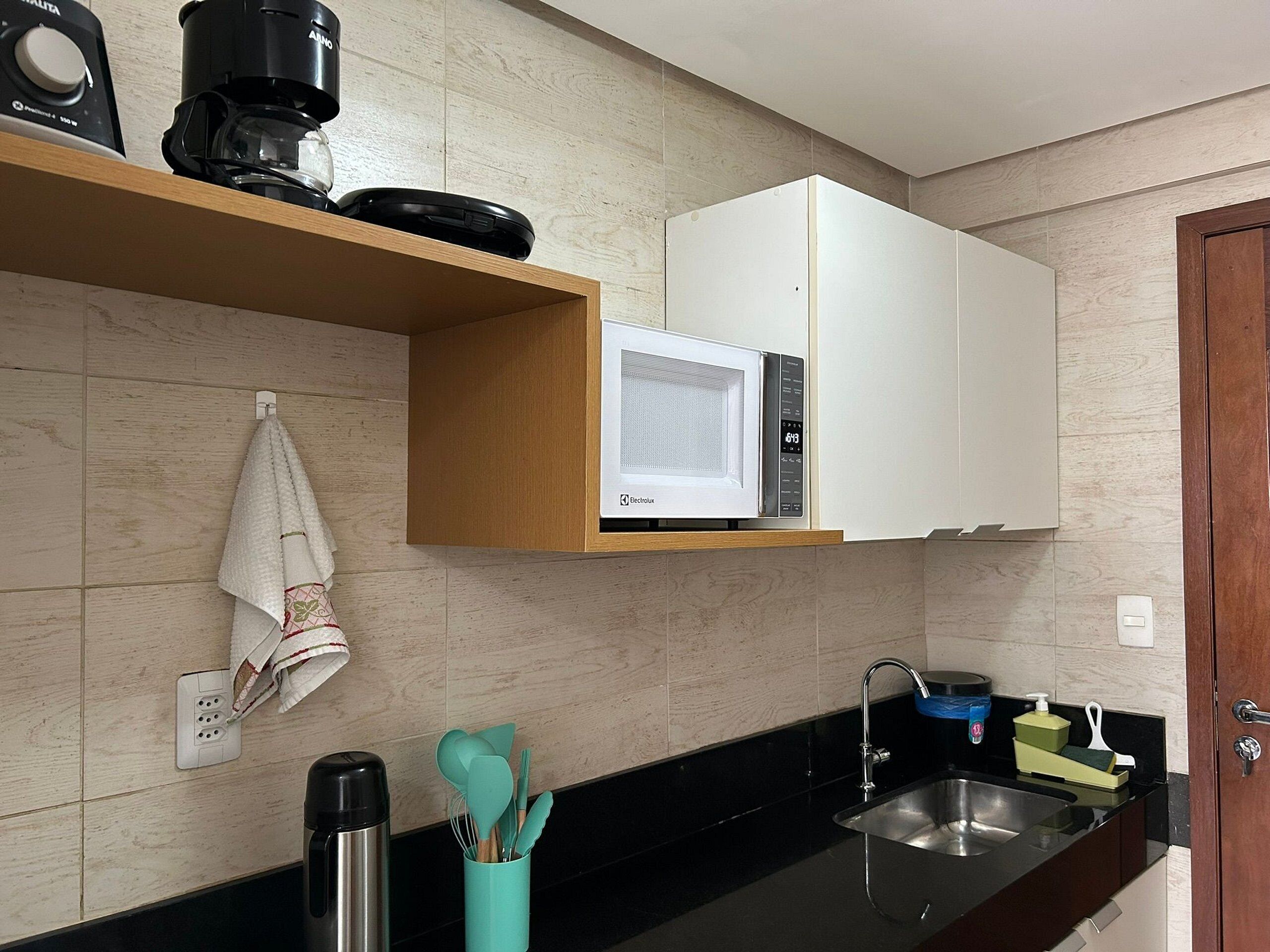 A kitchen with a microwave, coffee maker, and a sink.