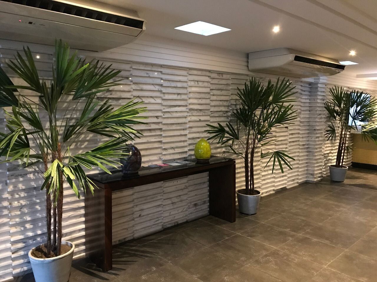 Un espace d’accueil comprenant un comptoir de réception, des plantes en pot et un mur à motifs.