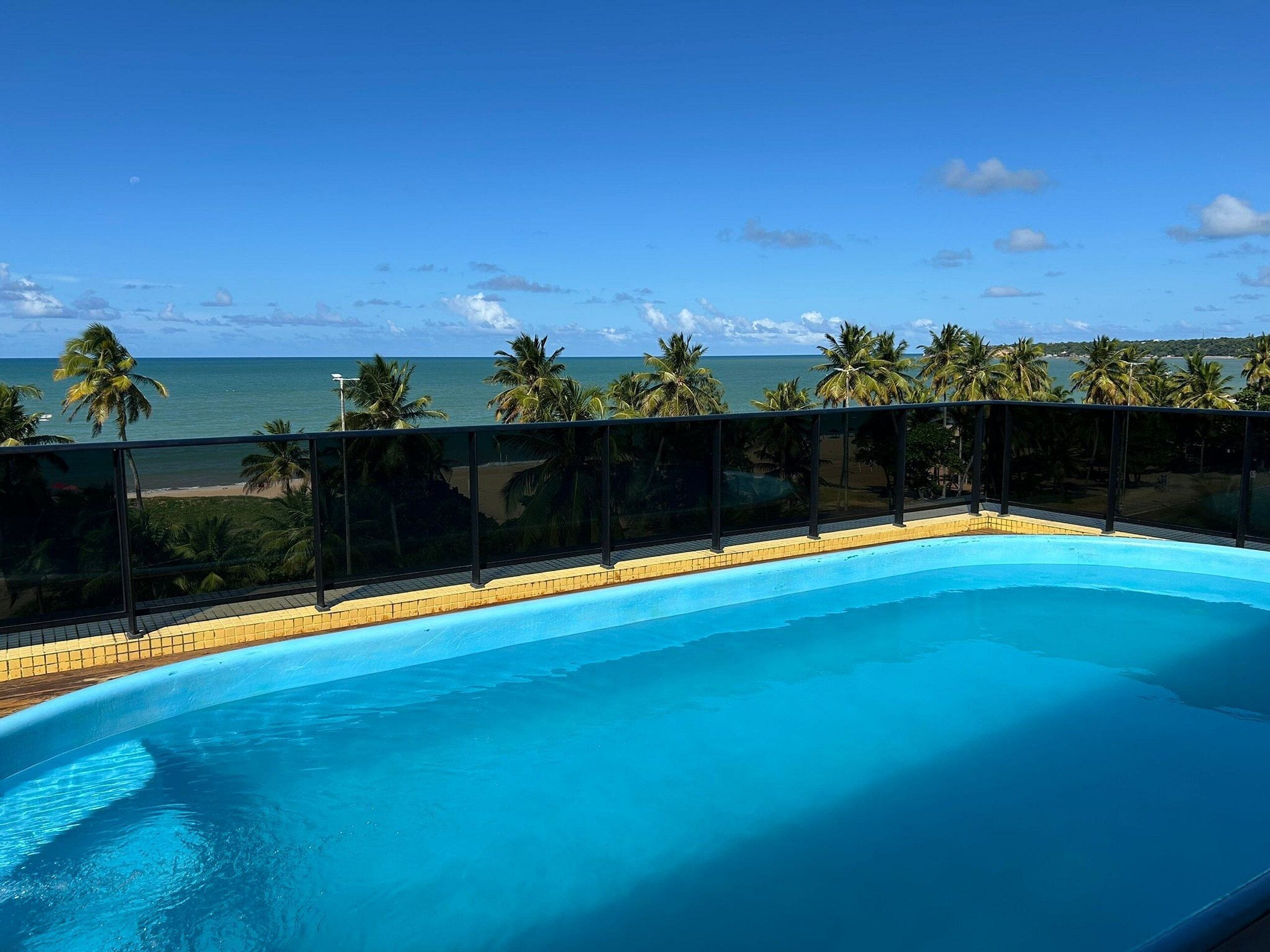 A swimming pool with a clear view of the ocean and palm trees.