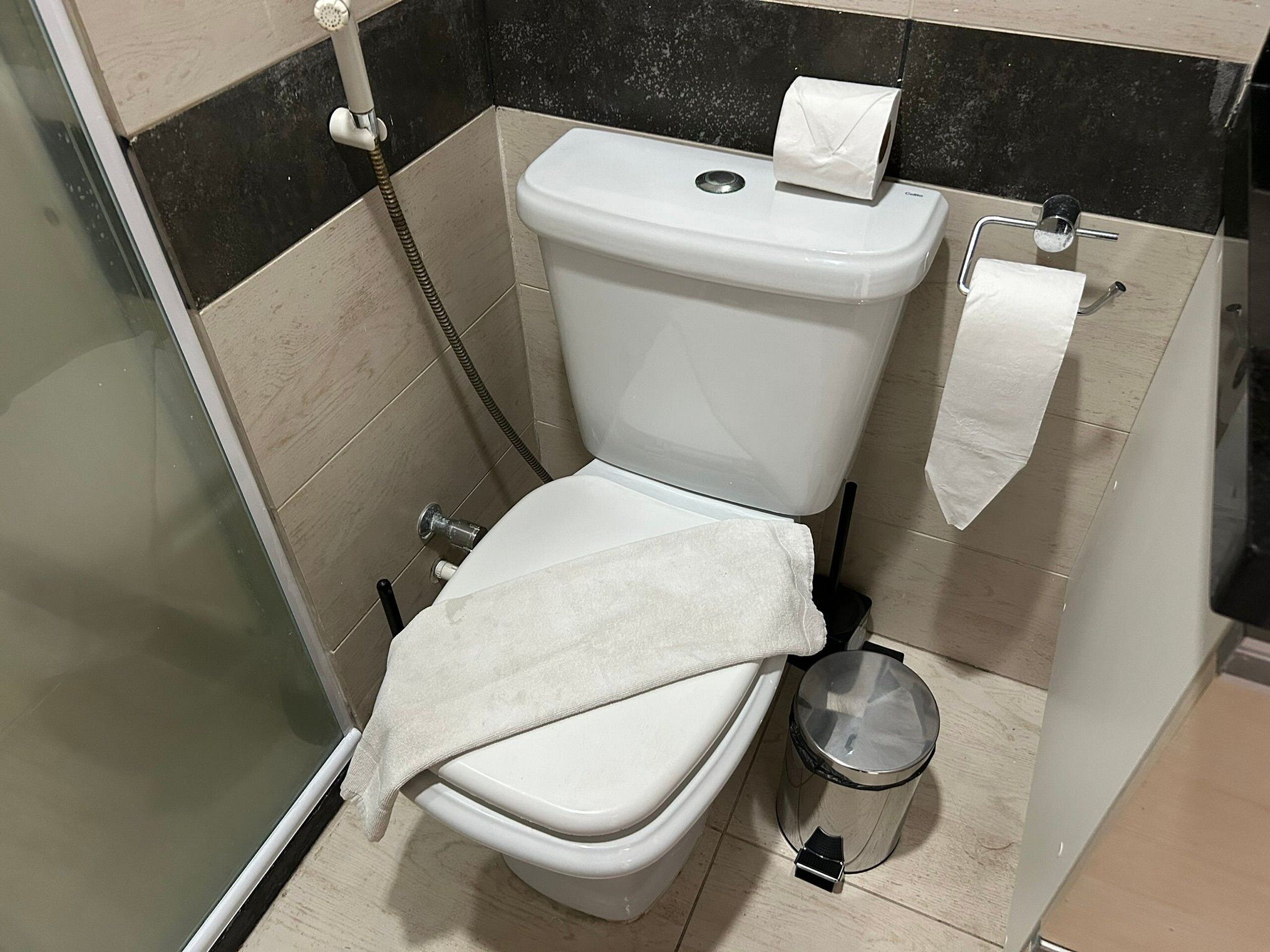 Een badkamer met een toilet, een douche en een prullenbak.