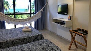 Una camera d'albergo con un letto, un'amaca, una TV e vista sull'oceano.