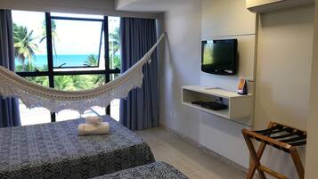 Habitación de hotel con cama, una hamaca, televisor y vista al océano.