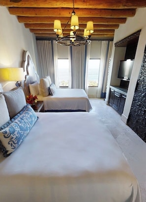 A hotel room with a large bed, a TV, a desk, and a view of the sea. - Luxury Villa in 5 Star Resort (Cabo San Lucas)