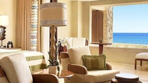 A spacious living room with a view of the sea, featuring two armchairs, a coffee table, and a lamp. - Luxury Villa in 5 Star Resort (Cabo San Lucas)
