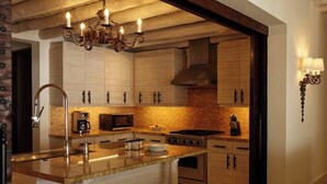 A modern kitchen with a central island, stainless steel appliances, and a hanging light fixture. - Luxury Villa in 5 Star Resort (Cabo San Lucas)